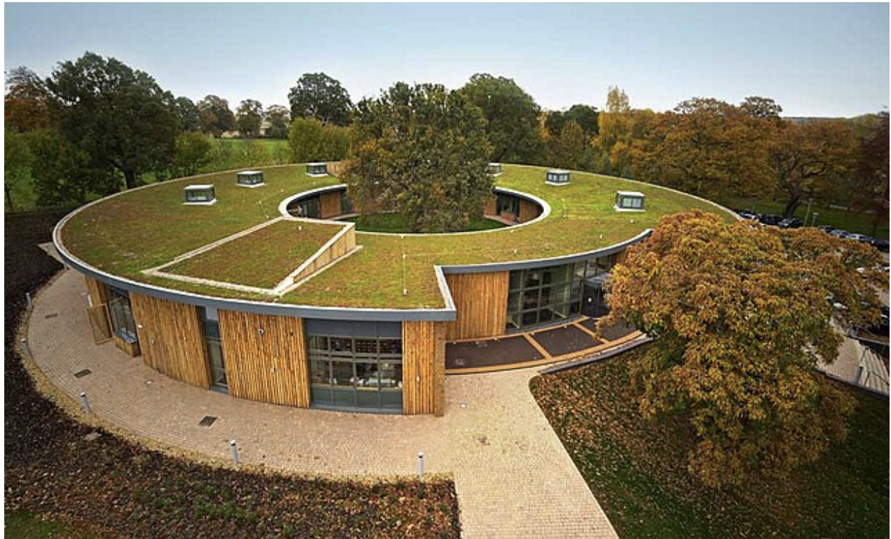 Brown building in a circular shape with a green roof